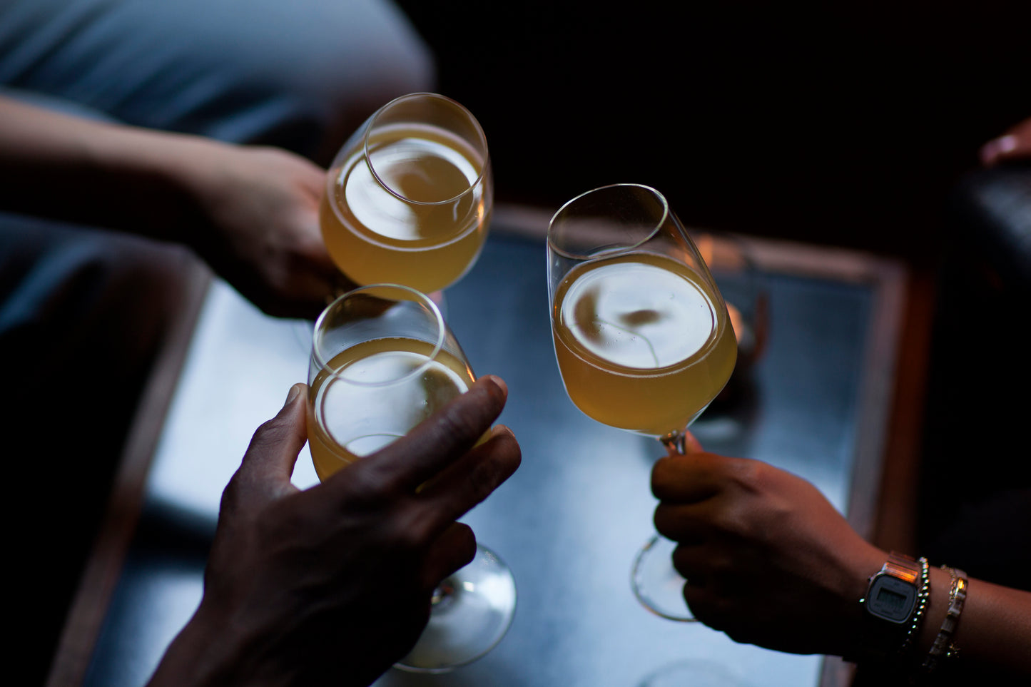 Three people toasting at a local and stylish Vesterbro bar, with flavourful lowalcoholic kombucha.
